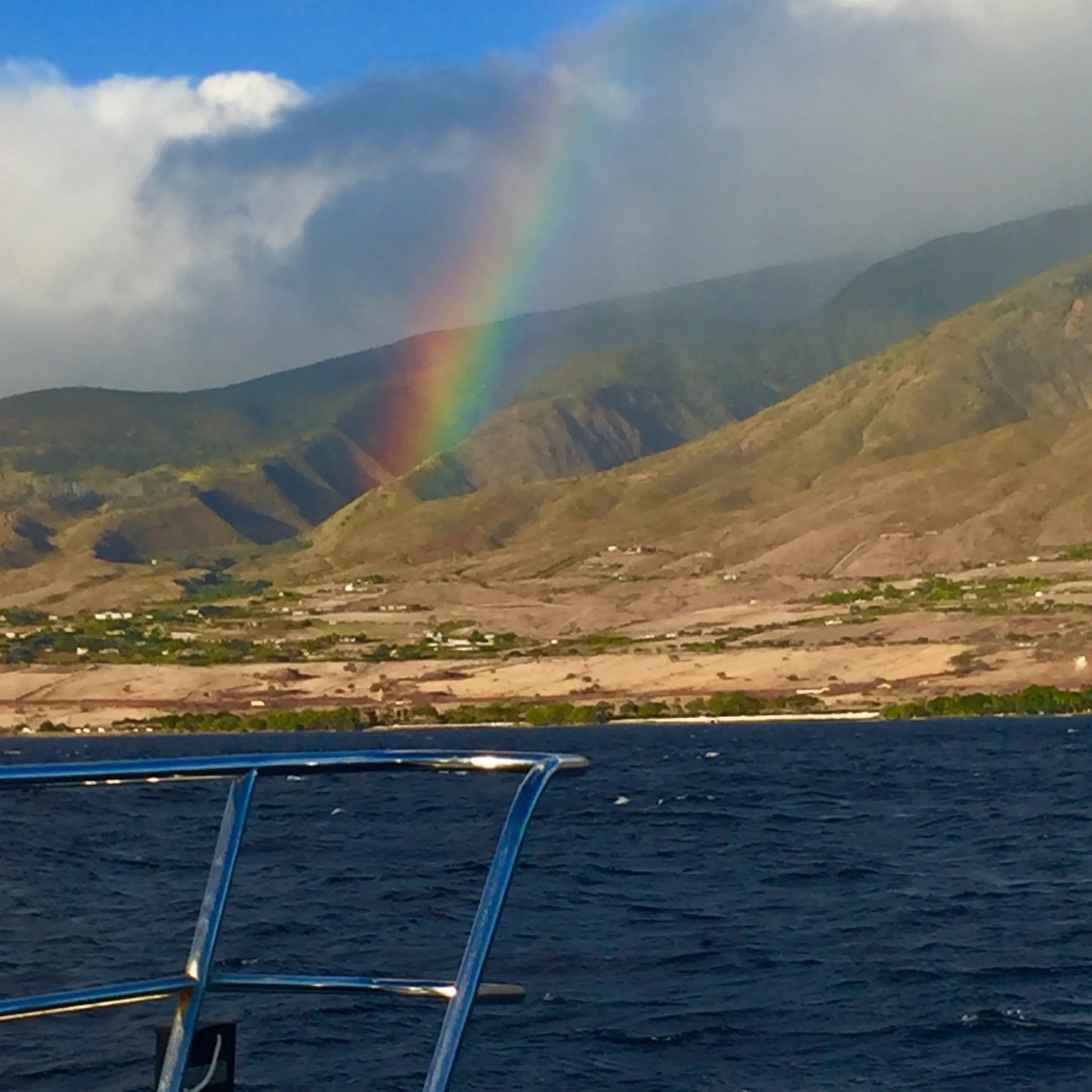 Rainbow seen from the water along a mountain coastline